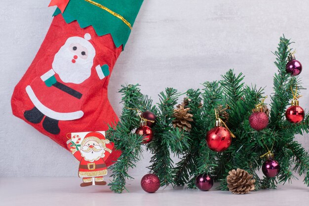 Chaussette de Noël pleine de boules de fête sur une surface blanche