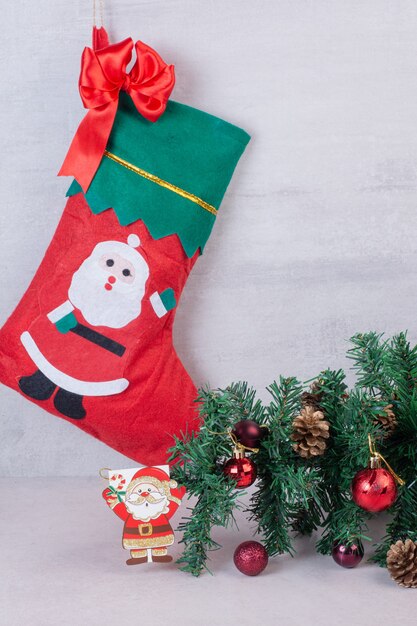 Chaussette de Noël pleine de boules de fête sur une surface blanche