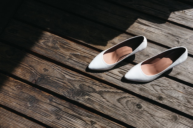 Les chaussures de mariage de la mariée se tiennent sur un plancher en bois en plein air