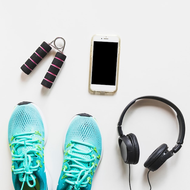 Photo gratuite chaussures de sport turquoise; casque de musique; téléphone portable et poignée sur fond blanc