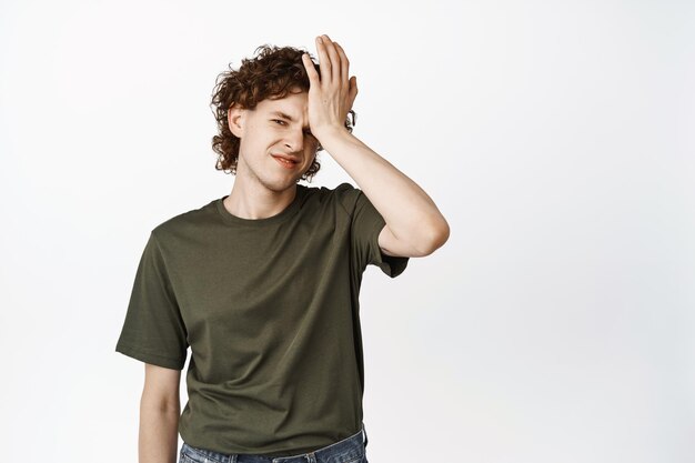 Échec Jeune adolescent facepalm à la recherche de déçu et bouleversé debout en t-shirt sur fond blanc