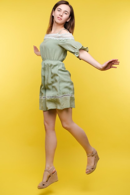 Cheerful brunette young woman in casual outlook sautant dans les airs en studio