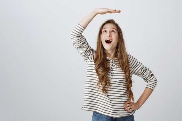 Cheerful girl lever la main au-dessus de la tête et avoir l'air étonné