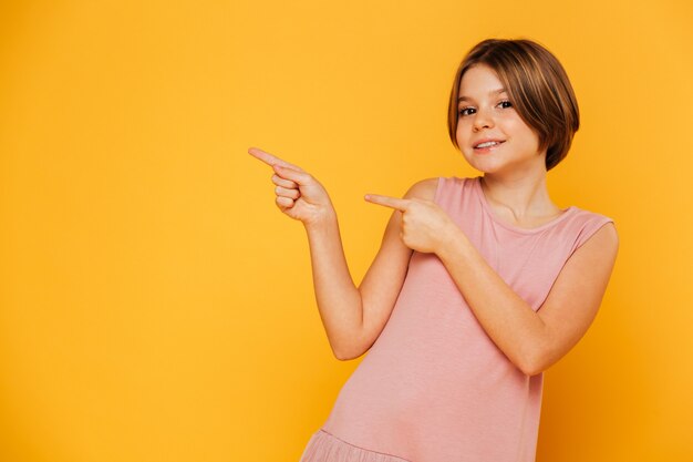 Cheerful lady in dress looking camera and pointing at copy space