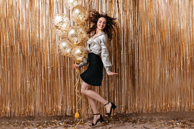 Cheerful lady in silver blouse sautant sur fond d'or