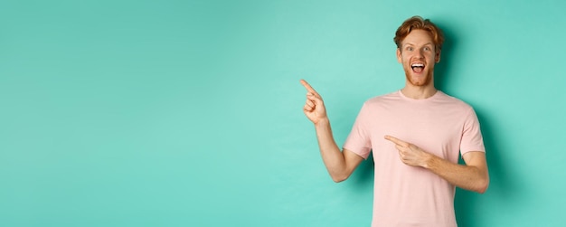 Cheerful man in tshirt à la recherche de happy pointant du doigt vers la gauche et montrant l'offre promo standin