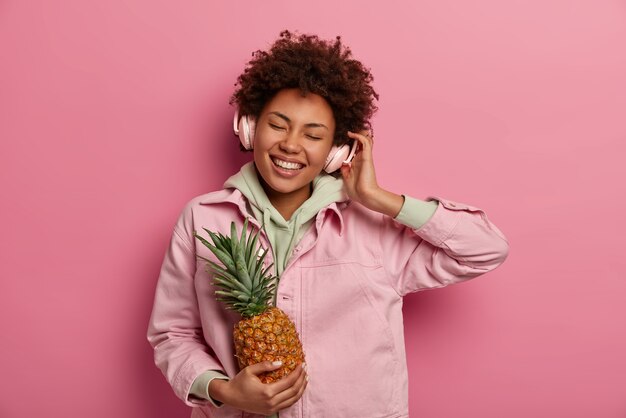 Cheerful millennial woman écoute de la musique et bénéficie d'un excellent son dans les écouteurs