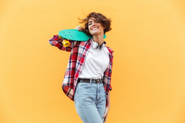 Cheerful young teenage girl holding skateboard sur ses épaules