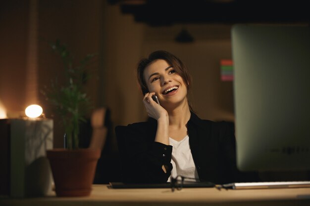 Cheerful young woman designer parler par téléphone