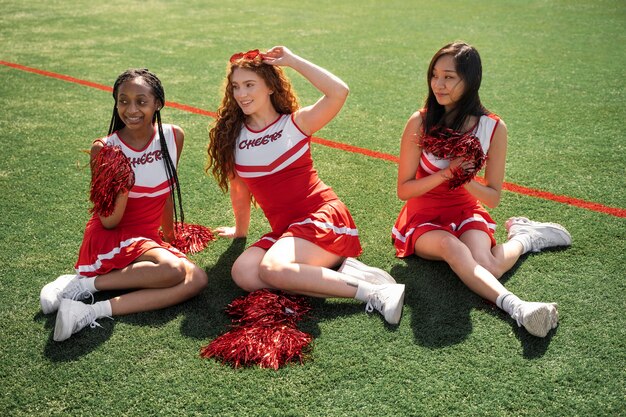 Cheerleaders plein coup assis sur l'herbe