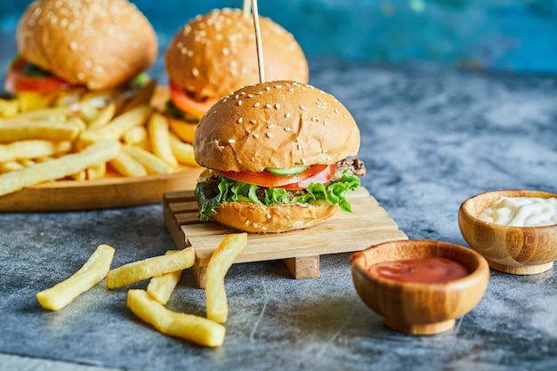 Cheeseburgers avec pommes de terre frites sur la planche de bois