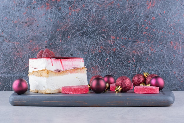 Cheesecake avec bonbons et boules de Noël sur plaque sombre. photo de haute qualité