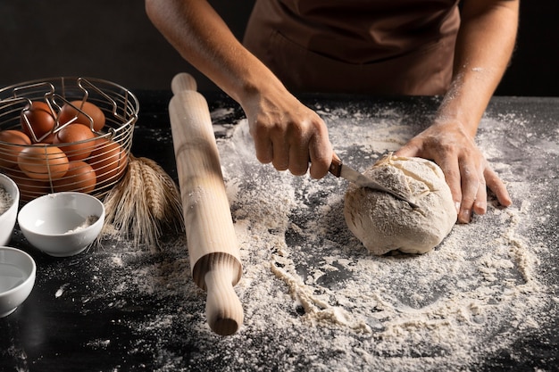 Photo gratuite chef couper la pâte à pain sur la table