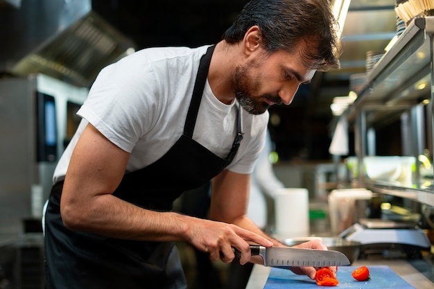 Photo gratuite chef cuisinant dans la cuisine en portant une tenue professionnelle