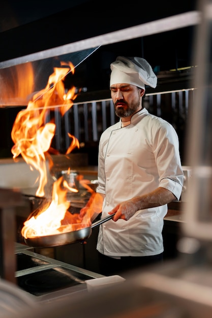 Chef cuisinant dans la cuisine en portant une tenue professionnelle