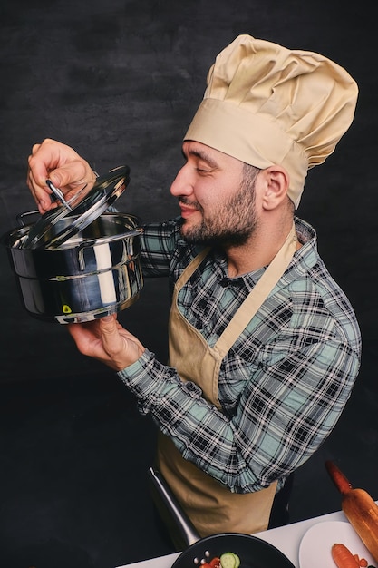 Chef cuisinier barbu drôle dégustant la soupe d'une casserole.