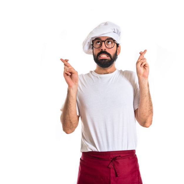 Chef avec les doigts croisés sur fond blanc