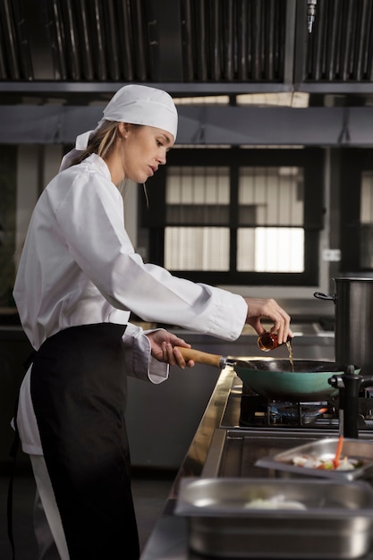 Photo gratuite chef féminin dans la cuisine faisant frire la nourriture