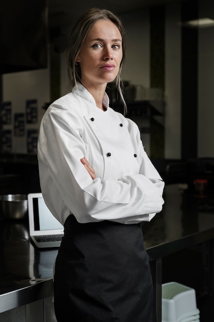 Chef féminin dans la cuisine habillé en tablier et uniforme