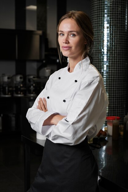 Chef féminin dans la cuisine habillé en tablier et uniforme