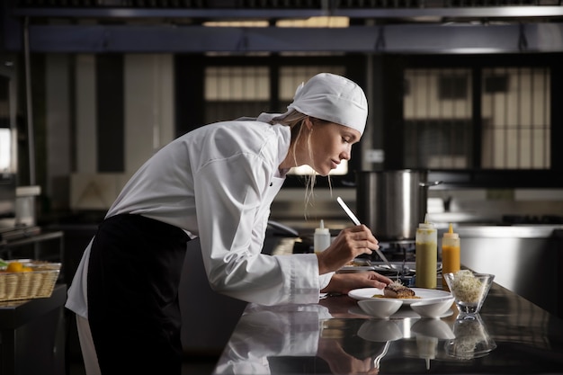 Photo gratuite chef féminin dans la cuisine préparant le plat du bifteck