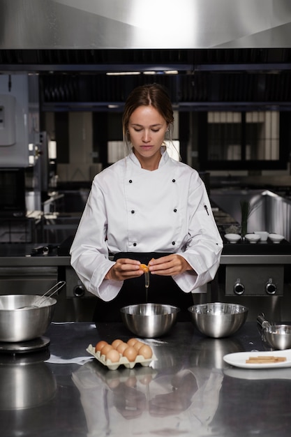 Chef féminin dans la cuisine séparant les œufs dans un bol