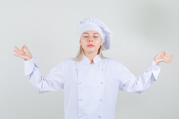 Chef féminin faisant la méditation avec les yeux fermés en uniforme blanc et l'air détendu.