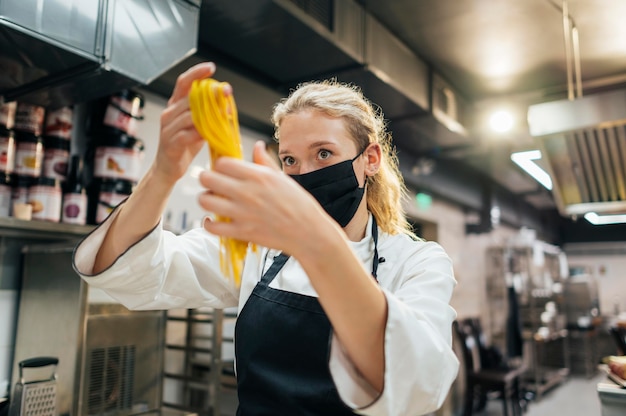 Chef féminin avec masque tenant des pâtes fraîches