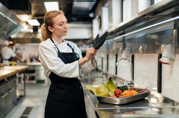 Chef féminin mettant des gants dans la cuisine