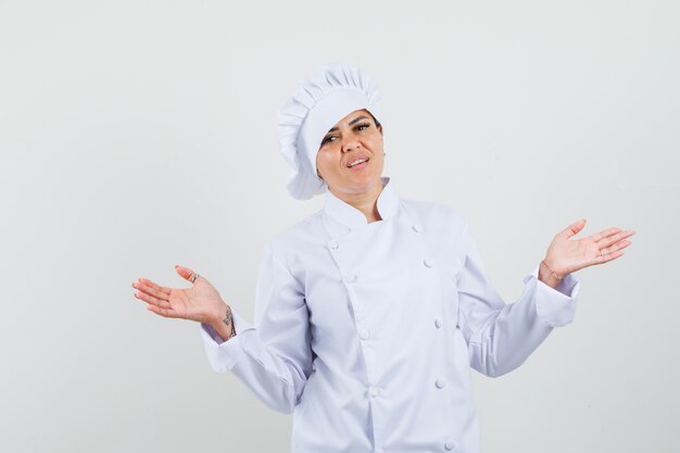 Chef féminin montrant un geste perplexe en uniforme blanc