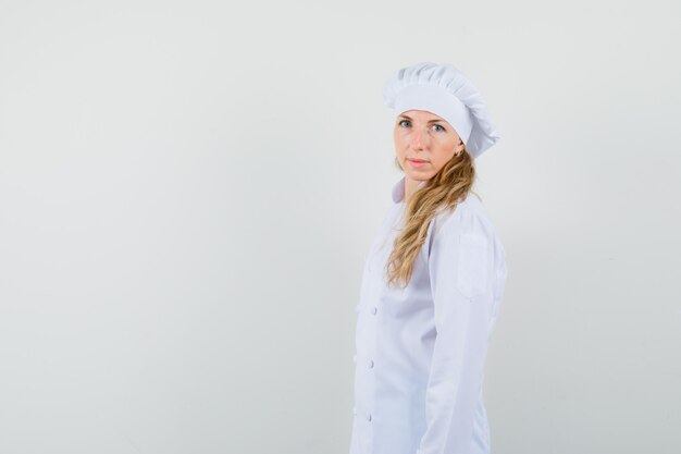 Chef féminin regardant la caméra en uniforme blanc et à la recherche sensible. .