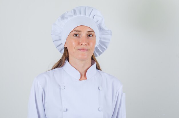 Chef féminin souriant et regardant la caméra en uniforme blanc