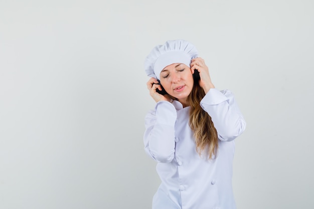 Chef Féminin En Uniforme Blanc Appréciant La Musique Avec Des écouteurs