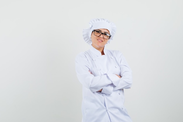 Photo gratuite chef féminin en uniforme blanc debout avec les bras croisés et l'air confiant.