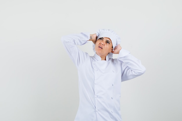 Chef féminin en uniforme blanc étreignant la tête avec les mains