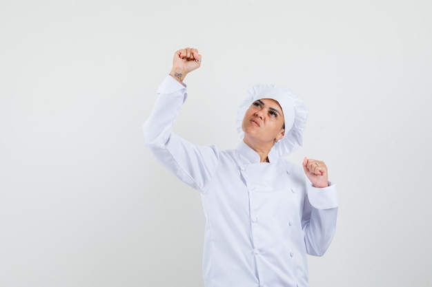 Chef féminin en uniforme blanc montrant le geste du gagnant et à la chance