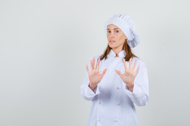 Chef féminin en uniforme blanc montrant le geste de refus et à la confiance