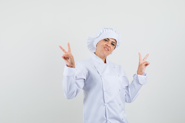 Chef féminin en uniforme blanc montrant le geste de la victoire et à la joyeuse