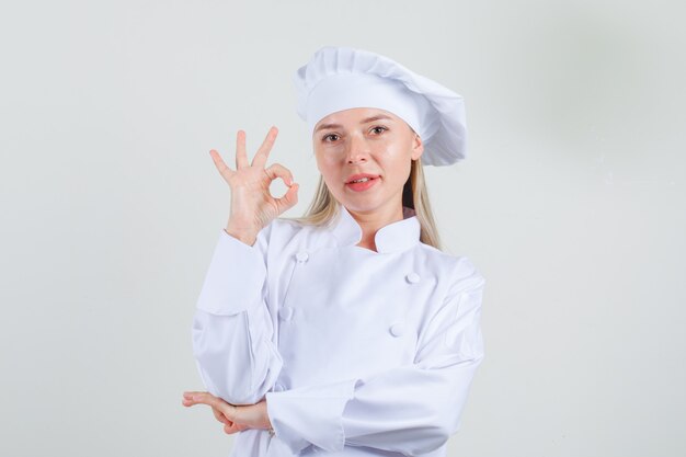 Chef féminin en uniforme blanc montrant signe ok et à la recherche positive