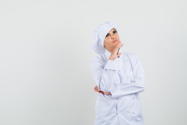 Chef féminin en uniforme blanc à la recherche et à la pensive