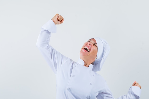 Chef de femme montrant le geste du gagnant en uniforme blanc et à la béatitude