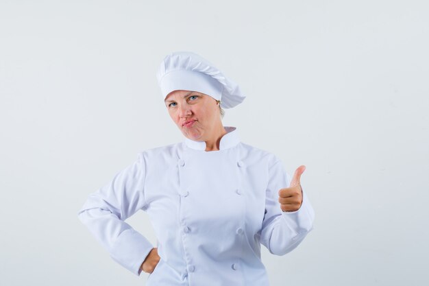 Chef de femme montrant le pouce vers le haut en uniforme blanc et à la satisfaction