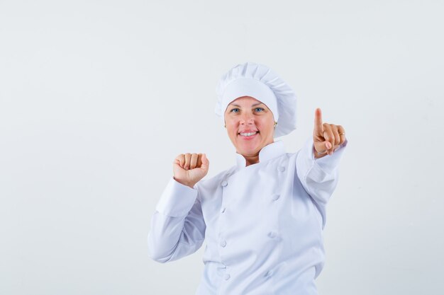 Chef de femme pointant vers l'avant tout en montrant son poing en uniforme blanc