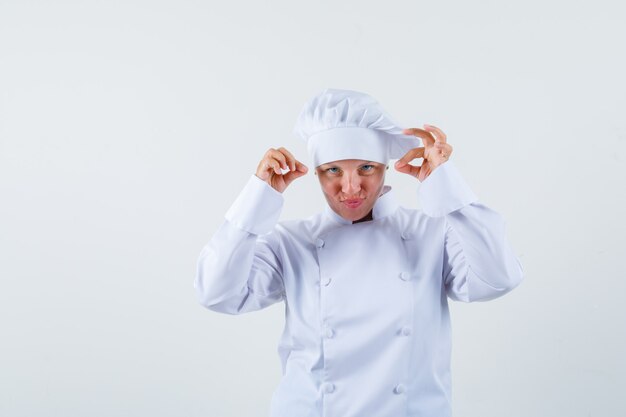 Chef de femme posant comme saupoudrer de sel en uniforme blanc et à la recherche concentrée