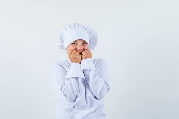 Chef de femme tenant les mains sur les joues en uniforme blanc et à la mignon