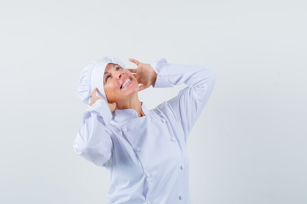 Chef de femme en uniforme blanc faisant semblant d'utiliser des écouteurs et à ravi