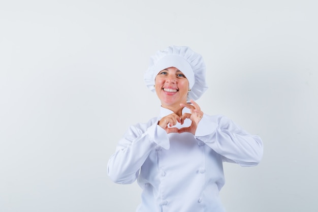 Chef de femme en uniforme blanc montrant le geste du cœur et à la joyeuse