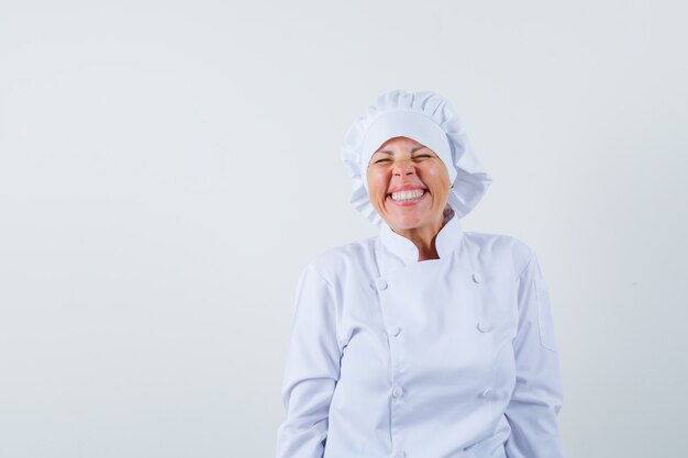 Chef de femme en uniforme blanc riant les yeux fermés