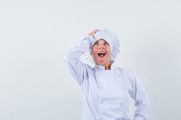 Chef de femme en uniforme blanc tenant la main sur la tête et à la surprise