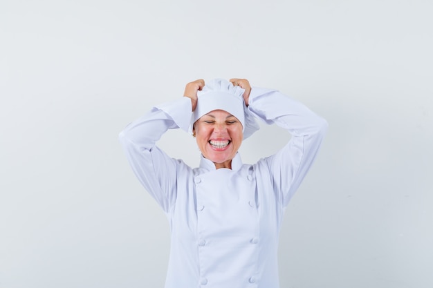 Chef de femme en uniforme blanc tenant les mains sur la tête et à la chance